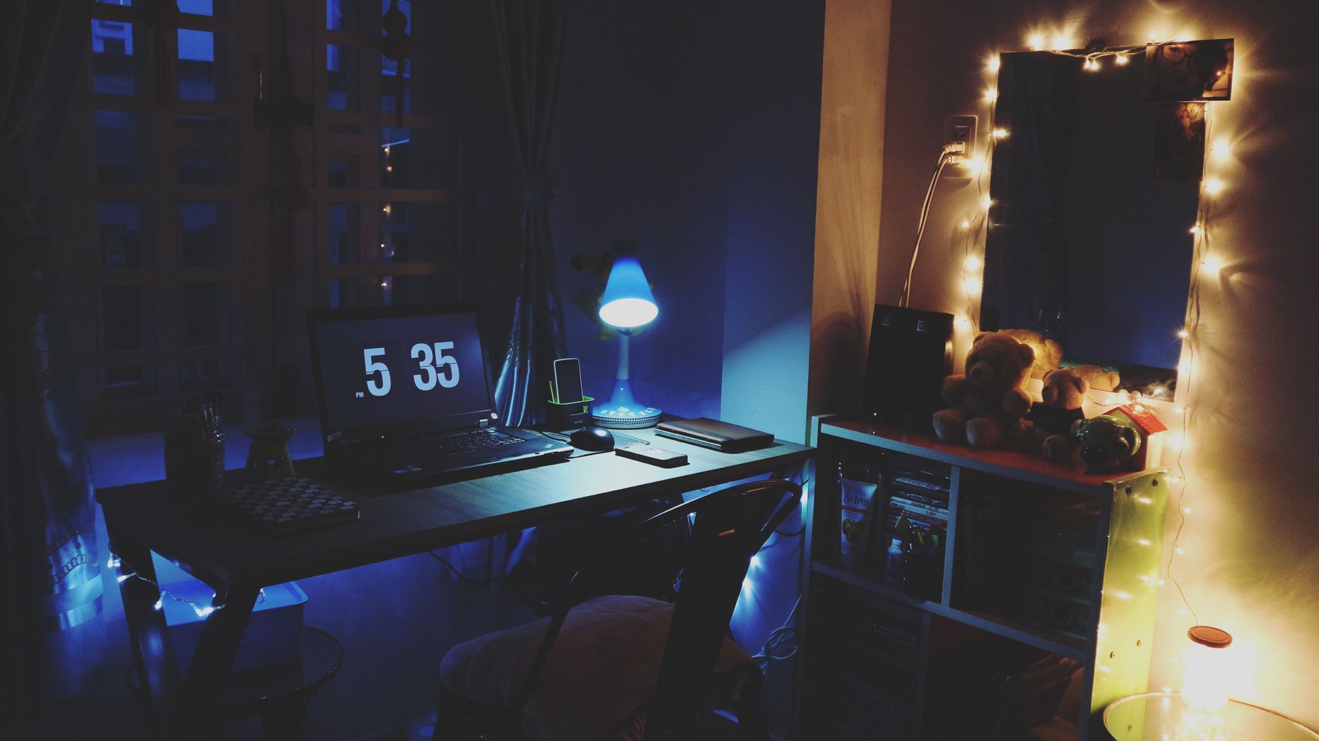 Bureau chaleureux en soirée, avec un ordinateur portable et une guirlande lumineuse.