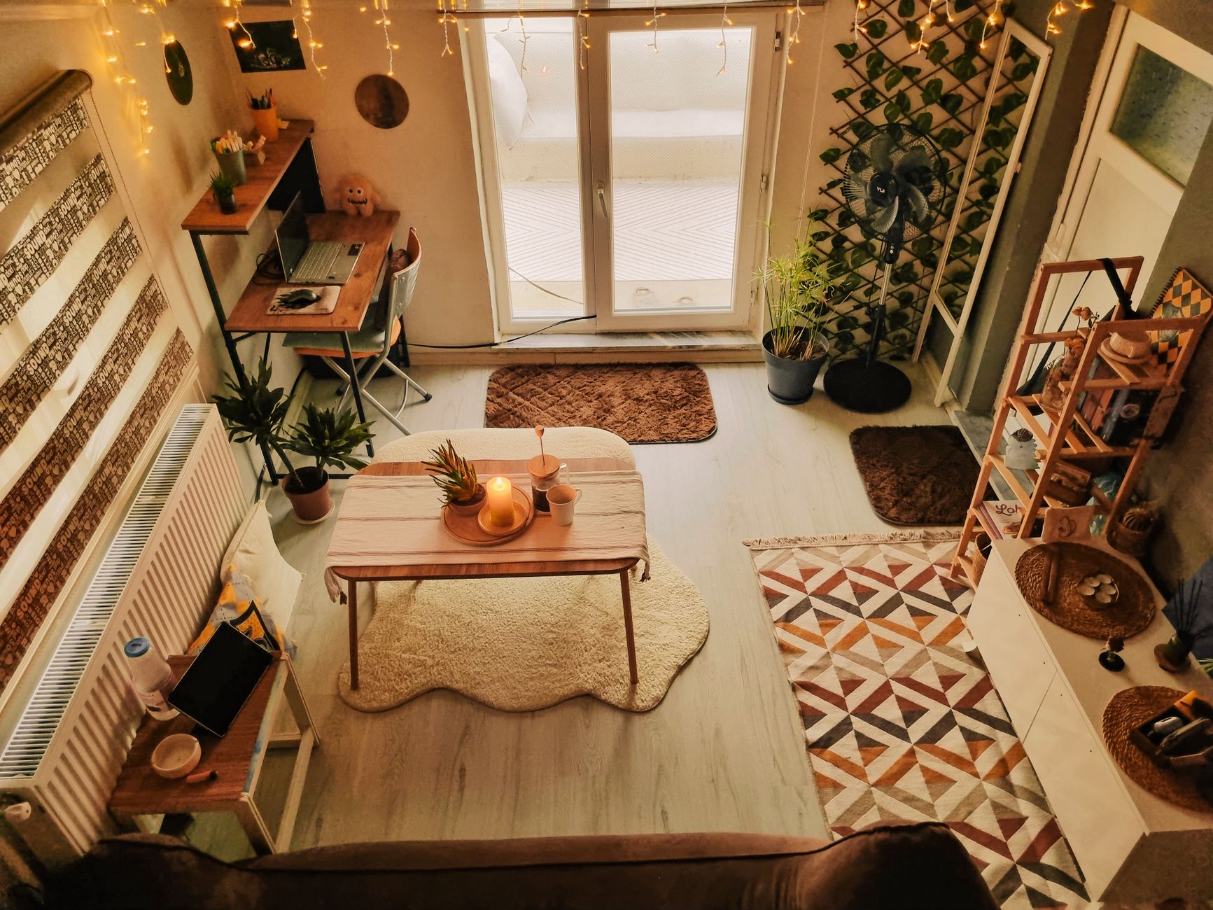 Salon chaleureux avec un bureau en bois, des plantes d'intérieur et des lumières décoratives.