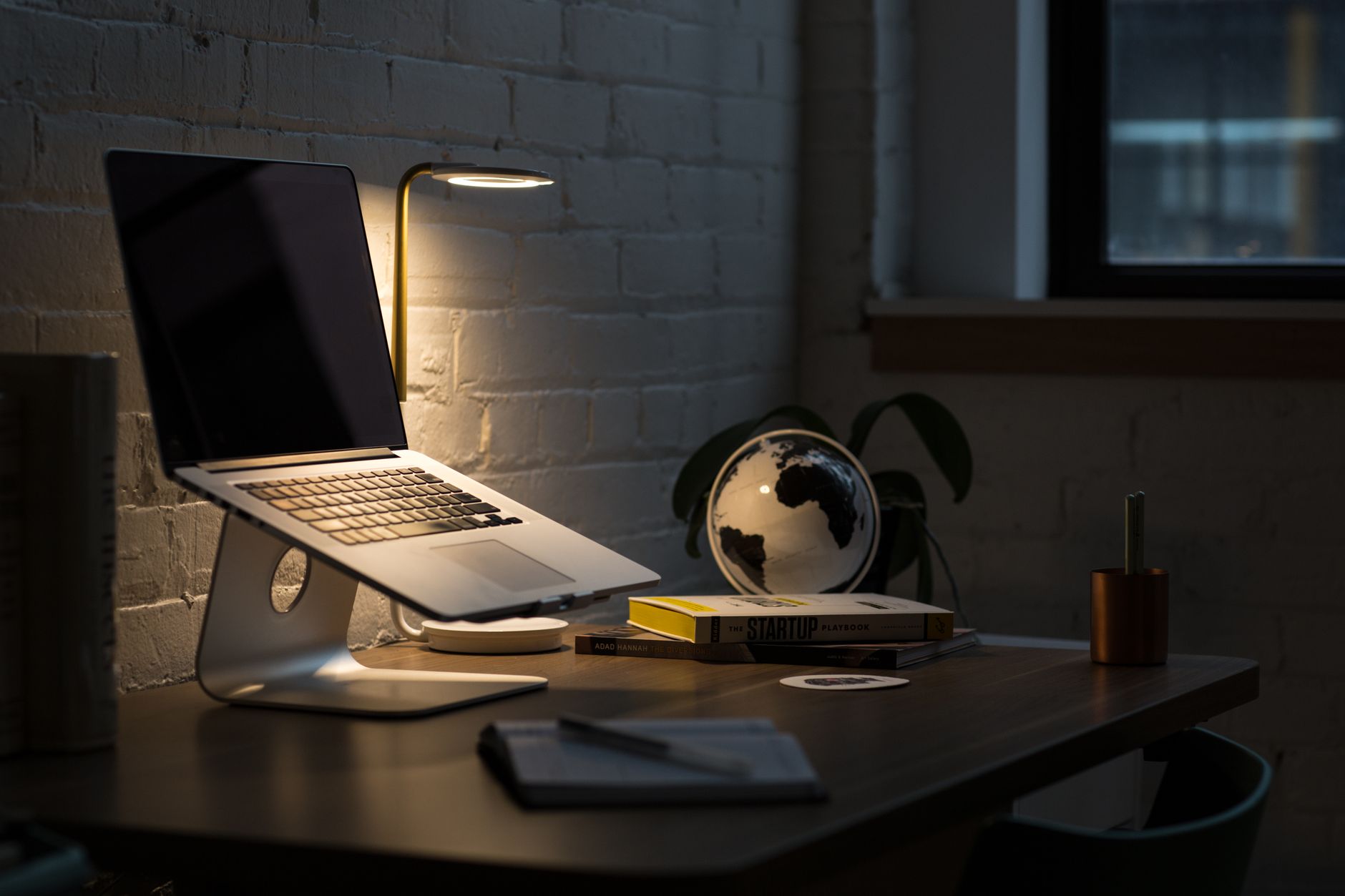 Espace de travail moderne avec un ordinateur portable, des livres et un éclairage ambiant.